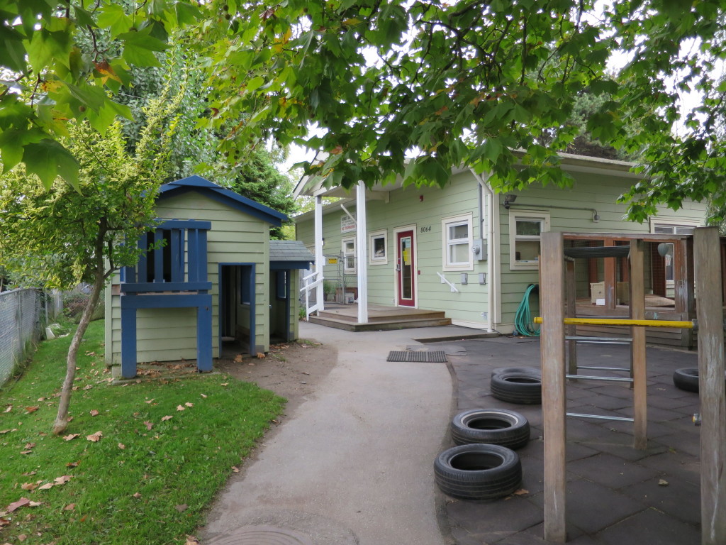 The playhouse and the daycare entrance at 8064 Buscombe Street, under a big maple